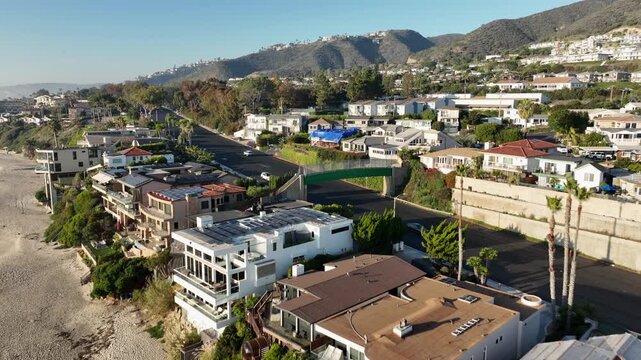 Laguna Beach, California, USA - Aerial View Moving From Pacific Coast Highway Toward Hillside Neighborhood With Beachfront Homes, Coastal Residences and Scenic Hills on a Sunny Day