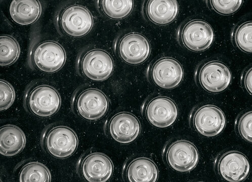 Repeating circular silver LED lights arranged across a dark textured panel with reflective surfaces and high tech geometric detail, abstract lighting texture