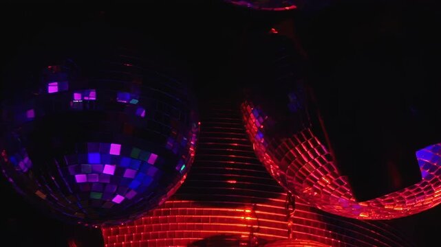Disco Balls Scatter Red and Purple Reflections in a Dark Interior. Reflective spheres fill the dark interior while tiled mirror surfaces scatter changing light into colorful abstract patterns.