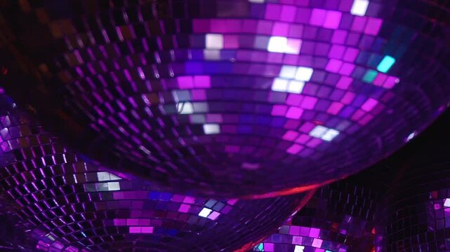 Disco Ball Cluster Shimmers With Blue and Purple Reflections. The grouped mirror balls fill the frame as mirrored mosaic surfaces catch changing colored light and form an abstract pattern.