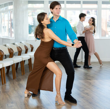 Couple of young guy and young woman dancing latin dances in studio