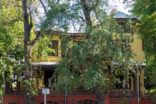 Historic twentieth century wooden art nouveau Nosov mansion facade hidden behind green trees in Moscow Russia