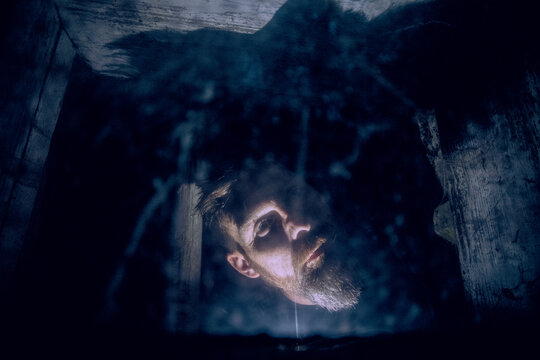 scary man behind window with spider nets at night Halloween horror background