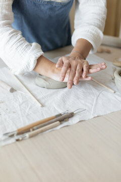 Potter artist forming clay in a focused and creative ceramic studio side view with white and gray tones and wooden tools, artistic hobby and crafting visual resource for web banners and posters.