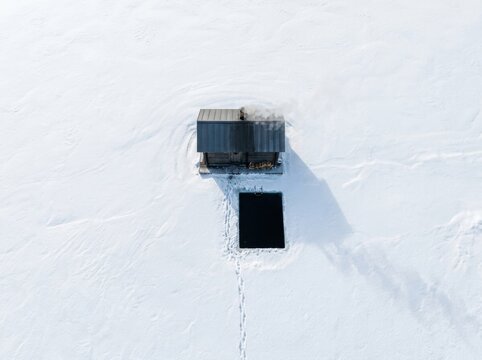 Remote shack in vast snowfield with smoke and frozen winter solitude