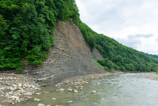 Mountain river flowing past rocky cliffs and green forest in the Carpathians