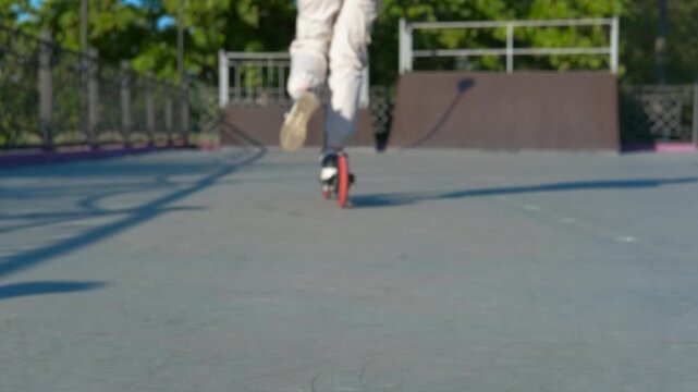 Teenager riding push scooter in skate park. Young athlete perfecting push scootering skills at skate park, executing dynamic tricks with fluid movement and confident balance while