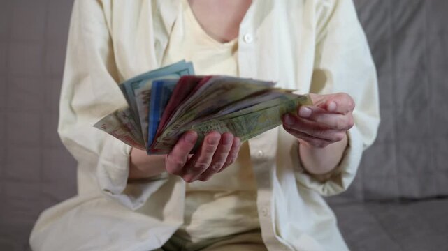 Various international currency banknotes. Woman sitting and carefully counting a large wad of cash with various international currency banknotes, illustrating global finance