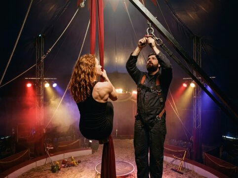 Aerial silk training in circus tent with performer and rigger