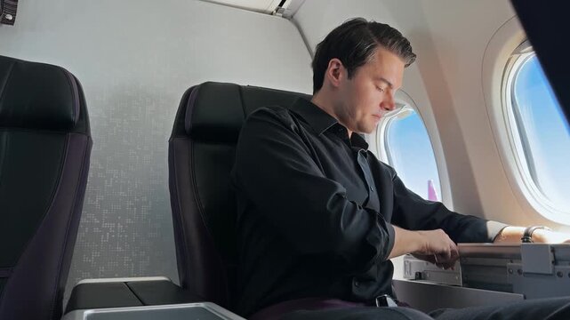 Businessman Typing on Tablet on Plane Tray Table During Flight