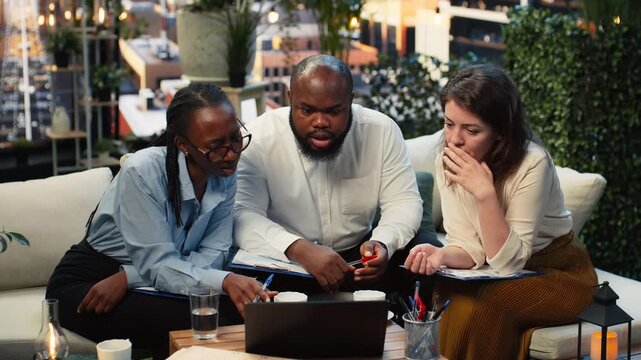 Businesspeople react negatively to unexpectedly low performance metrics on a laptop while analyzing document charts to identify the issue.