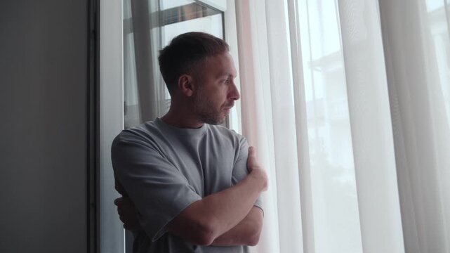 Loneliness, social isolation and midlife crisis concept with pensive man by window facing uncertainty, contemplation, sadness, solitude and difficult decision.