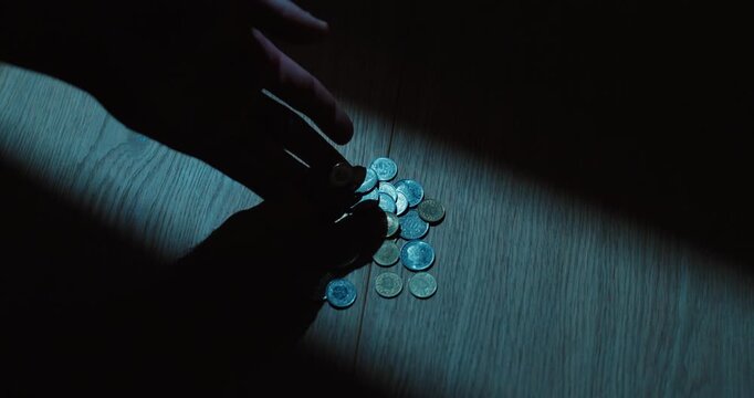 Person empties coins onto a table by hand, representing money, savings and personal budgeting.