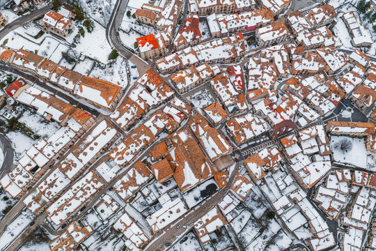 Aerial view of the historic village of Pescocostanzo with snow-covered terracotta rooftops and narrow stone streets in Pescocostanzo, Abruzzo, Italy.