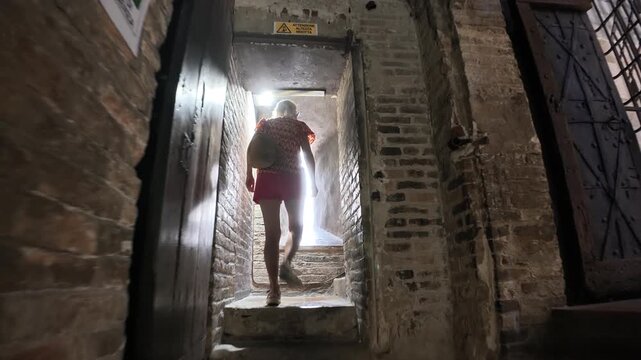 tourist woman on the stairs of the panoramic view inside the Ghirlandina bell tower, showcasing the striking architecture of Modena's revered Duomo cathedral of Modena city in Italy