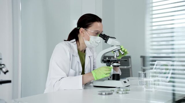 Scientist operates microscopy in a sterile lab, analyzing specimens with advanced equipment and preparing cultures for experimental studies in a specialized biology facility