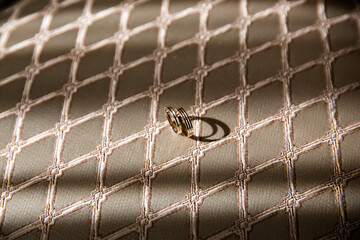 Obraz premium Gold wedding rings on quilted beige fabric