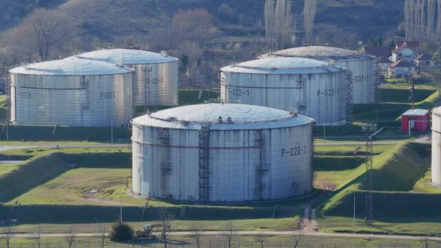 Large silver oil storage tanks at modern petroleum refinery facility