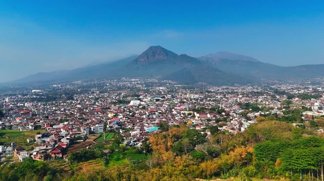 Aerial view of Batu city with Panderman mountain in the background in Batu, East Java, Indonesia.