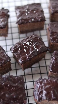 Garnishing chocolate cake slices with flaky salt. Vertical video.