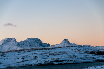 Landscape shot highlighting the rugged mountains and snow-covered beaches of arctic norway during a brief golden hour during the long winters. © Goldilock Project