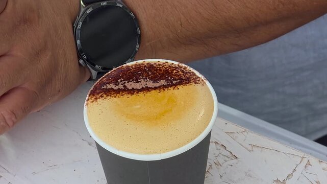 Close up shot of barista hands decorating cappuccino coffee foam with chocolate syrup topping using a squeeze bottle at Festival Gastronomic  