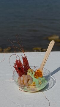 Camera movement showing luxury gourmet dish with red Denia prawn, green avocado cream and salmon caviar served in a bowl by the sea at  Festival Gastronomic in Spain.