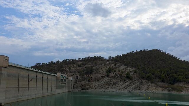 Time lapse of heavy storm clouds darkening the sky over the Amadorio dam and reservoir surrounded by hills in Alicante province, Spain.