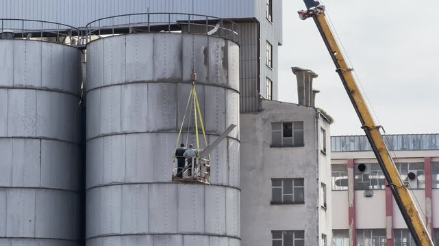 Industrial Workers Performing Silo Maintenance with Crane Lift