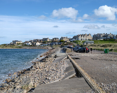 Coastal erosion damaging the concrete promenade and road surface along the scenic seafront of Lossiemouth in the Moray region of Scotland