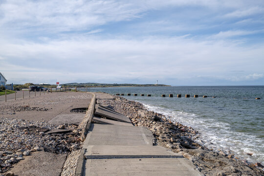 Coastal erosion damage along the shoreline of Lossiemouth in Moray Scotland showing broken pavement sections near the North Sea during the day
