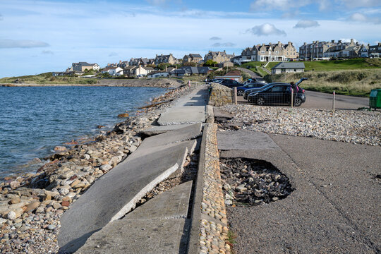 Coastal storm damage with broken pavement and eroded ground in Lossiemouth, Moray, Scotland