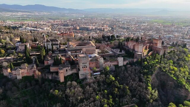 Aerial view of Alhambra Historic Fortress / Palace in Granada, Spain, showing fortress line, charles v palace, granada cityscape, and alcazaba. Orbit parallax shot