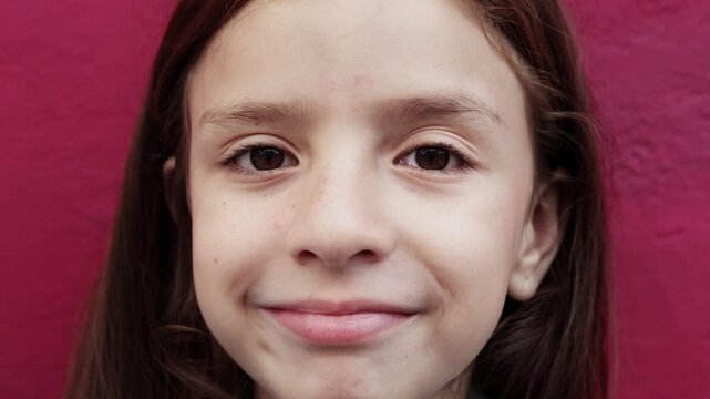 Happy redhead girl looking at camera in closeup pink background - Childhood portrait concept