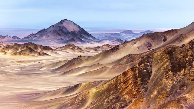 Rugged desert mountains and sharp rocky ridges rise dramatically from a vast arid landscape under a clear blue sky during daylight.