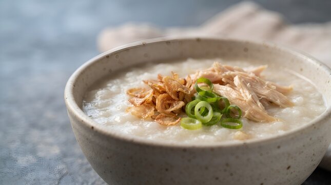 Bowl of traditional Asian chicken rice porridge congee with scallions and fried shallots.