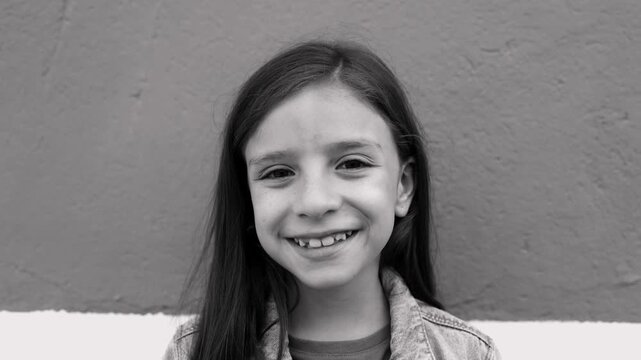 Cheerful redhead girl smiling at camera on pink background - Childhood and lifestyle portrait concept - Black and white edit