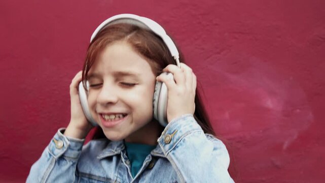 Happy redhead child listen playlist music with headphones outdoor - Technology trends