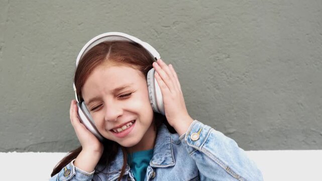 Happy redhead child listen playlist music with headphones outdoor - Technology trends