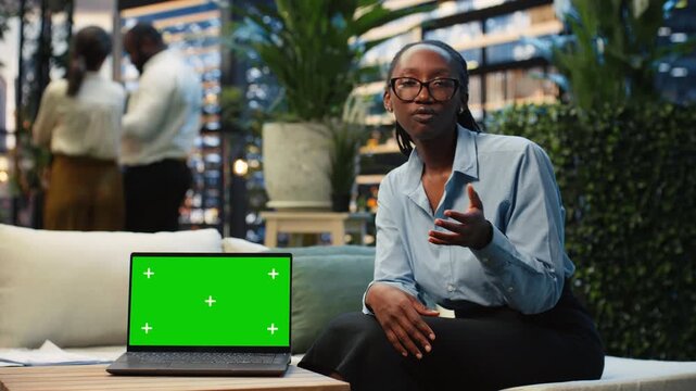 Businesswoman uses a green screen laptop to explain project information on a rooftop workspace, with a chroma key notebook supporting her work tasks.