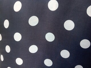 Close-up of women's dress fabric featuring large white polka dots on black background, soft woven textile texture, classic retro polka dot pattern, stylish casual fashion  © Ramdan