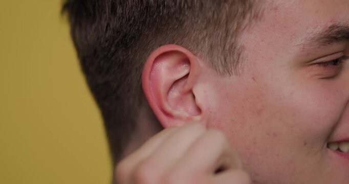 Man demonstrates ear cleaning technique for improved hygiene and health in a close-up shot with a vibrant background