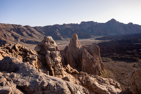 Sharp rock spires rise above the sunlit floor of the Las Canadas caldera in Teide National Park. Dramatic volcanic geology for adventure travel and science content.