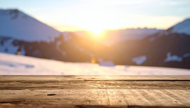 Wooden table surface with blurry snowy mountain landscape background at sunset ideal for displaying products in a winter setting