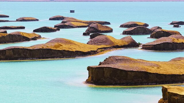 Unique yardang landforms rise above turquoise waters in Qinghai Water Yadan Geopark, capturing an extraordinary arid desert landscape under bright day.