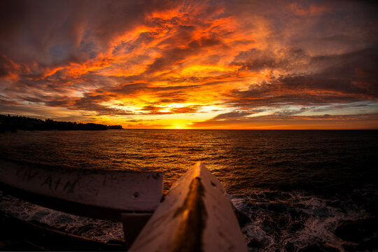Dramatic sunrise illuminates clouds and ocean waves from a water-level perspective at Bronte Beach in Sydney, Australia.