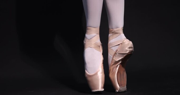 Ballerina in pointe shoes training on black background, closeup