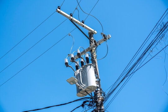 Power pole and overhead cables against blue sky