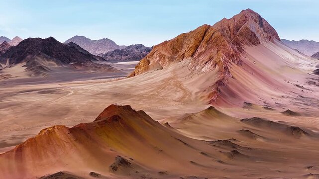 Majestic view of sharp mountain ridges and vast sand dunes stretching across a remote desert under daylight.