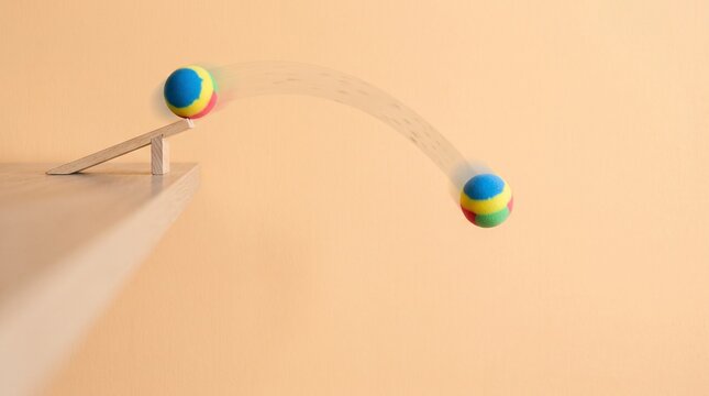 Colorful foam ball rolling down a wooden ramp showing parabolic motion